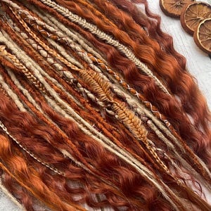 May include: A set of brown, orange and blonde synthetic dreadlocks with woven braids. The dreadlocks are wavy and have a natural look.