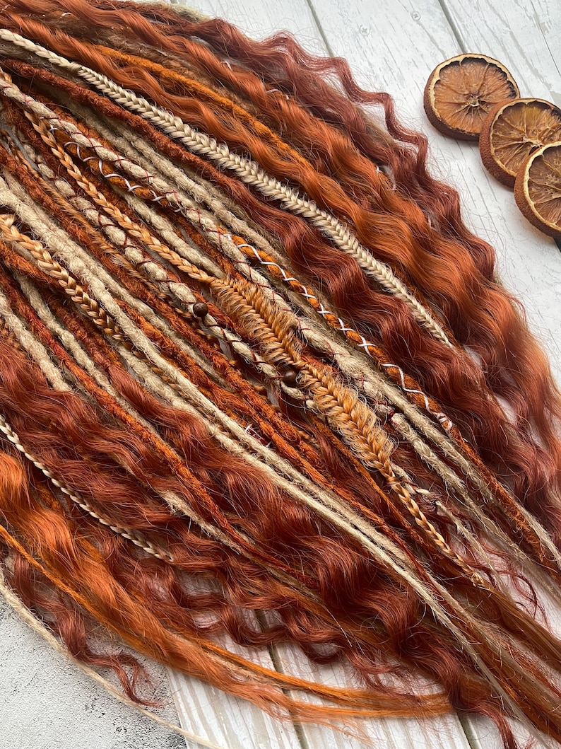 May include: A set of brown, orange and blonde synthetic dreadlocks with woven braids. The dreadlocks are wavy and have a natural look.