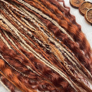 May include: A set of synthetic dreadlocks in shades of brown, beige, and blonde. The dreadlocks are long and wavy, with some featuring decorative beads and braiding.