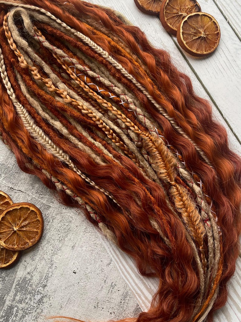 May include: A set of brown, blonde, and beige synthetic dreadlocks with wavy textures. The dreadlocks are arranged in a loose bundle.