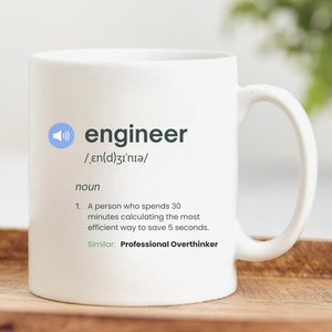 May include: White ceramic mug with a black and gray design. The mug features the word "engineer" with a definition and the phrase "Professional Overthinker".