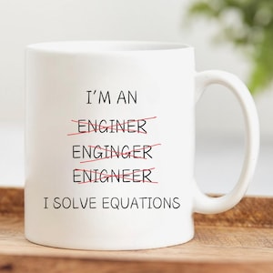 Puede incluir: Taza de cerámica blanca con texto negro que dice "Soy un ingeniero" con la palabra "ingeniero" tachada. El texto continúa con "Resuelvo ecuaciones".