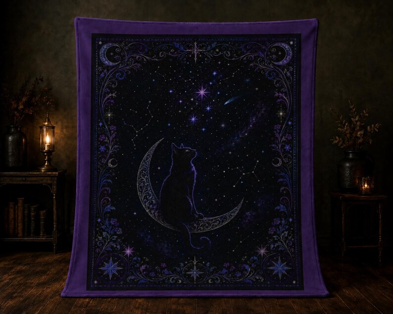 Puede incluir: Una manta rectangular con borde morado que presenta un gato negro sentado sobre una luna creciente. El dise&ntilde;o central muestra un cielo nocturno estrellado con constelaciones, rodeado por un borde floral y celestial en tonos azules.