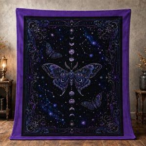 Puede incluir: Una manta rectangular con borde morado que presenta un gráfico central de una polilla grande rodeada de mariposas más pequeñas, una secuencia vertical de fases lunares y constelaciones estelares sobre un fondo cósmico azul marino.