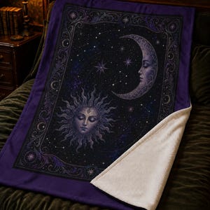 May include: A rectangular throw blanket featuring a dark purple and black celestial design with a central sun face and a crescent moon face surrounded by stars and constellations, framed by an ornate border with a white sherpa fleece underside.