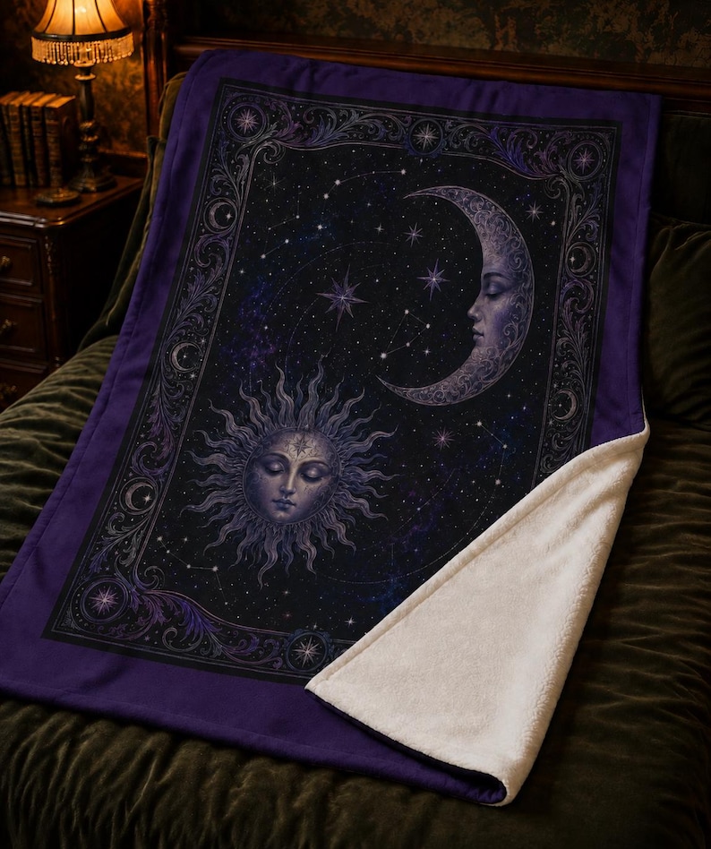 May include: A rectangular throw blanket featuring a dark purple and black celestial design with a central sun face and a crescent moon face surrounded by stars and constellations, framed by an ornate border with a white sherpa fleece underside.