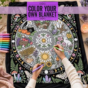Puede incluir: Una manta para colorear en blanco y negro con un diseño de rueda circular que incluye ilustraciones estacionales como calabazas, un conejo, trigo, girasoles y cristales. El texto COLOR YOUR OWN BLANKET está impreso en la parte superior.