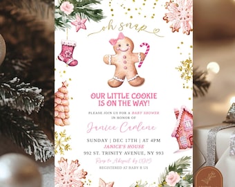 May include: A white baby shower invitation card featuring a gingerbread person with a pink bow and candy cane, surrounded by pink and gold holiday illustrations including snowflakes, a stocking, a tree, and a house with the text Oh snap our little cookie is on the way.