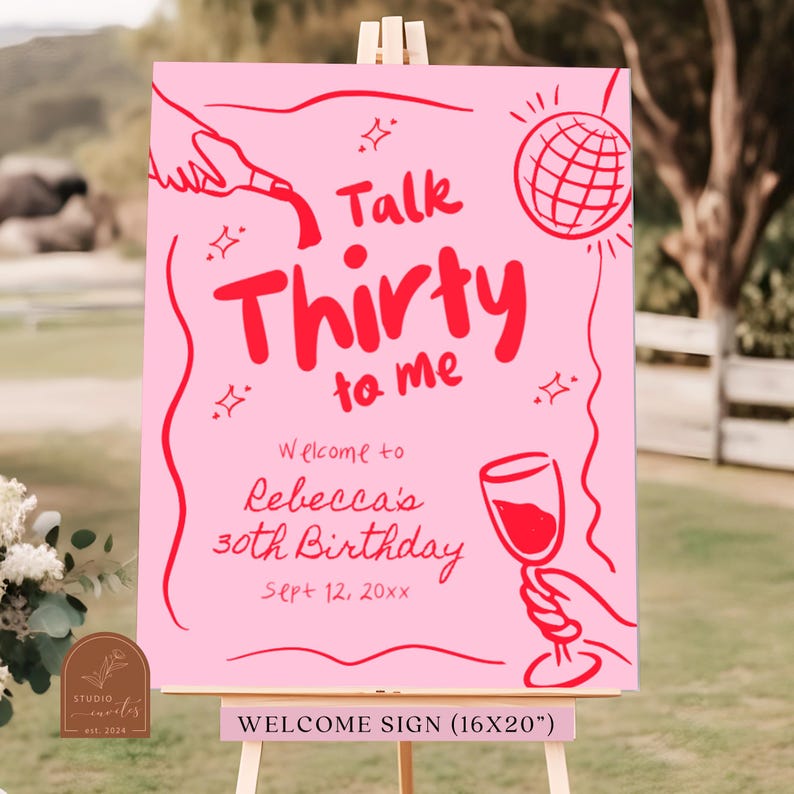 Op de afbeelding: Een roze welkomstbord met de tekst "Talk Thirty to Me" in rood. Het bord bevat ook een discobal, een glas wijn en de tekst "Welcome to Rebecca's 30th Birthday Sept 12, 20xx".
