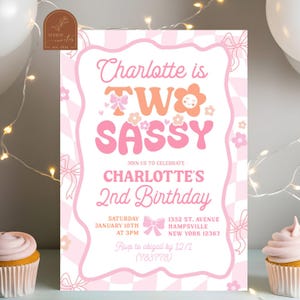 May include: Pink and white birthday invitation with the text "Charlotte is TWO SASSY" in a playful font. The invitation includes details for a second birthday celebration, with a floral and bow design.