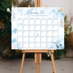 May include: A baby shower calendar sign on a wooden easel. The sign features a blue watercolor background with seahorse and whale illustrations. The text reads "Guess the Baby Due Date" with a calendar grid for guests to write their guesses.