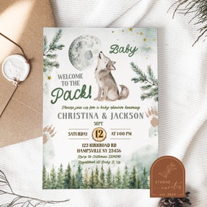Puede incluir: Una invitación a una fiesta de bienvenida al bebé con una ilustración de acuarela de un lobo aullando a la luna. La invitación es verde y dorada con el texto "¡Bienvenido a la manada!" y "Christina & Jackson".