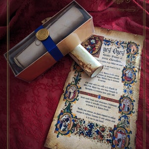 Puede incluir: Un juego de invitaciones de boda de estilo antiguo. El juego incluye un pergamino enrollado en una caja atada con una cinta azul y una invitación detallada con bordes y texto ornamentados. El fondo es una tela de color rojo oscuro.