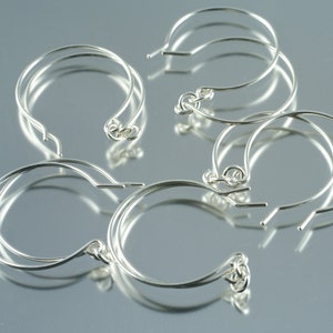 May include: Five silver hoop earrings with a simple, circular design. The hoops are made of thin wire and have a smooth finish.
