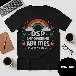 May include: Black t-shirt featuring a rainbow design and the text "DSP EMPOWERING ABILITIES. INSPIRING LIVES." The design includes hearts and other colourful shapes. A laptop, coffee, and glasses are in the background.