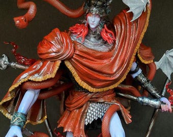 May include: A detailed figurine of a fantasy warrior with blue skin, red hair, and a red cape. The figure is adorned with snake-like appendages and bat-wing accents. It stands on a base with flames and candles, holding a staff with a fiery design.