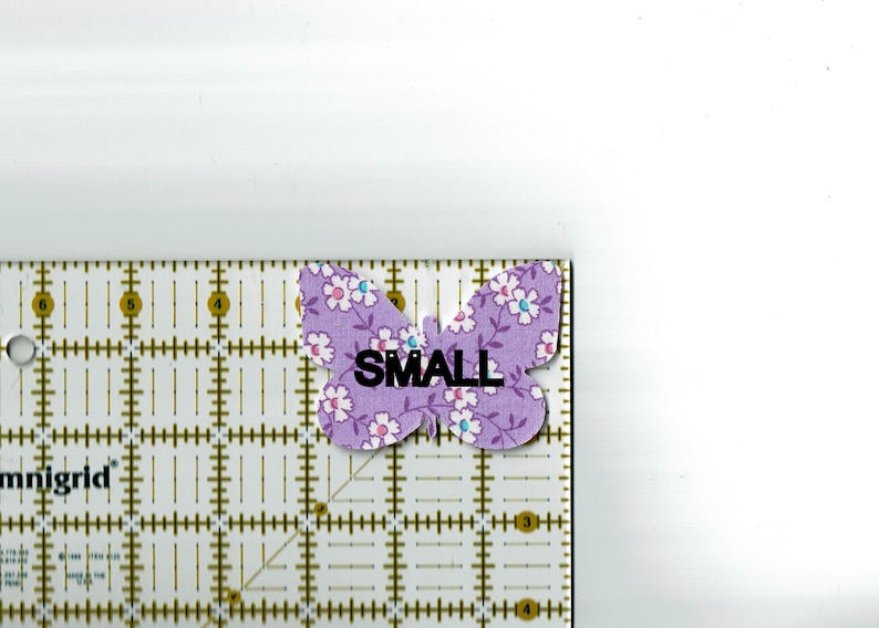 May include: A purple butterfly fabric applique with white flowers and the word "SMALL" printed on it.