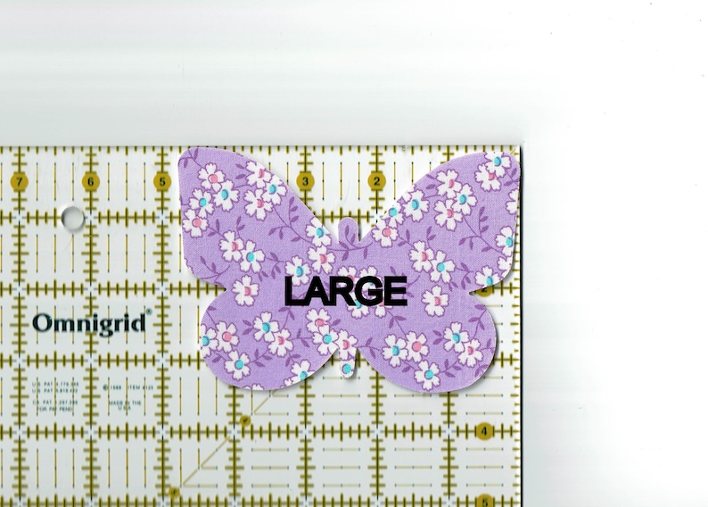 May include: A purple butterfly-shaped fabric patch with a white floral pattern and the word "LARGE" printed in black.