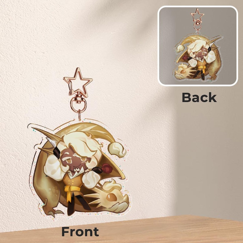 Op de afbeelding: Een heldere acryl bedel met een stripfiguur met blond haar en een gele outfit, rijdend op een gouden draak. De bedel heeft een stervormige sluiting en een ring. De achterkant van de bedel is ook zichtbaar in een kleinere afbeelding.