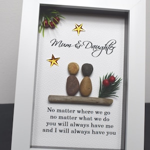 May include: A framed artwork featuring two pebble figures representing a mother and daughter, with the text "Mum & Daughter" and a quote about always having each other. The artwork includes a small twig, green foliage, and red berries.
