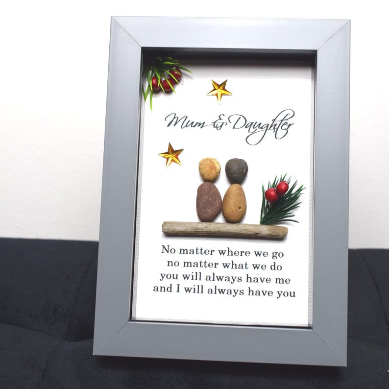 May include: A framed artwork featuring a pebble art design of two figures sitting on a piece of driftwood. The figures are labeled "Mum & Daughter" and the artwork includes the text "No matter where we go, no matter what we do, you will always have me and I will always have you".