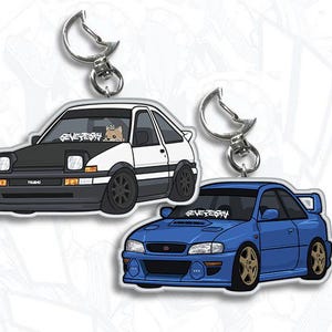 May include: Two car keychains, one white with black accents and the text "REVE7EKY" and the other blue with the same text. Both keychains feature cartoon illustrations of cars.