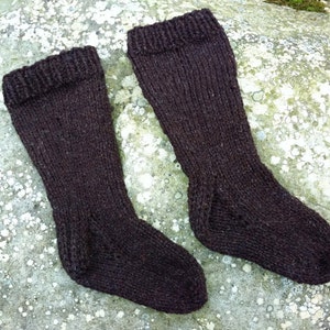 May include: A pair of brown knitted socks. The socks are made from a thick, textured yarn and have a ribbed cuff.