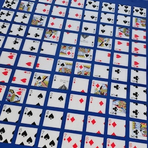 May include: A blue and white game board with playing cards arranged in a grid pattern. The cards are numbered 1 through 10 and include various suits, such as hearts, diamonds, clubs, and spades. The board is made of a sturdy material and is perfect for playing a game of cards with friends or family.