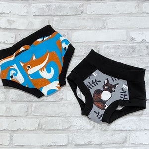 May include: Two pairs of colorful underwear with a black waistband. One pair features a blue and orange fox print, the other a gray and black cat print.