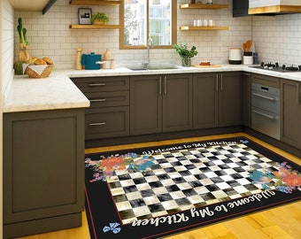 May include: A black and white checkered kitchen rug with floral accents and the text "Welcome to My Kitchen". The rug has a black border and is placed on a wooden floor in a kitchen setting.