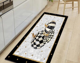 May include: A black and white checkered patterned rug with a gold border and a design of two black and white pumpkins with gold accents. The rug is on a light wood floor.