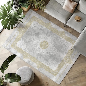 May include: A gray and gold area rug with a white floral pattern. The rug has a distressed look and a subtle sheen.