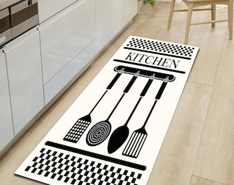 May include: Black and white kitchen rug with a checkered border and the word "KITCHEN" printed in the center. Four black silhouettes of kitchen utensils hang from hooks above the word.