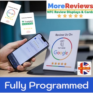 May include: A white NFC review display with a Google logo and five stars. The display has the text "Review Us On" and "Tap Here". A hand is holding a smartphone near the display. The display is on a table with a blue background. The text "More Reviews" and "NFC Review Displays & Cards" is at the top of the image. The text "Fully Programmed" is at the bottom of the image.