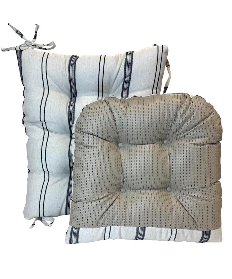 May include: Two square seat cushions. One is white with navy blue vertical stripes and ties. The other is a light beige with a textured pattern and button tufting. Both cushions have a striped border.
