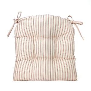May include: A square, padded seat cushion with a cream background and vertical red stripes. The cushion has a rounded top and is secured with cream-colored ties at the corners. The cushion is designed for comfort and style.