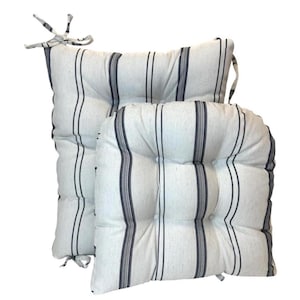 May include: Two white and navy striped seat cushions. The cushions have a tufted design with button detailing and ties for securing to a chair. The cushions are rectangular and rounded, with vertical stripes.