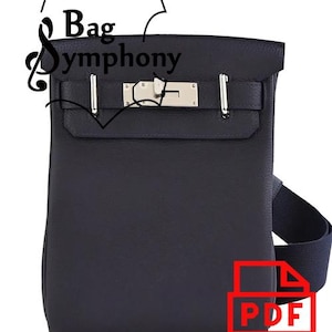 Puede incluir: Un bolso de cuero azul oscuro con una hebilla y una correa plateadas. El bolso tiene un asa superior y una correa para el hombro. El bolso está hecho de cuero de alta calidad y tiene un diseño clásico.