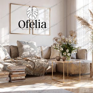 Può includere: Un soggiorno con un divano beige, opere d'arte con cornici dorate e un tavolino. Le opere presentano un design a foglia e il testo "Ofelia INTERIOR DESIGN". Un vaso di fiori e una pila di libri completano l'arredamento. Il tavolino è alto circa 40 cm.