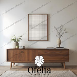 May include: A wooden console table with two drawers and four legs. The table is decorated with a vase of dried branches, a small potted plant, a mug, and a few books. A framed picture hangs on the wall above the table. The table is in front of a white wall and a rug.