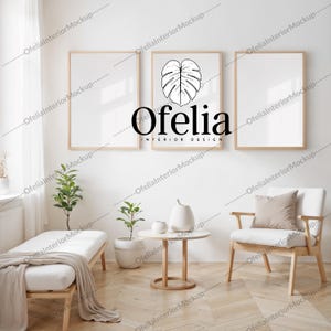 May include: A white living room interior design mockup featuring three framed prints, a white armchair with a beige cushion, a wooden bench with a white throw blanket, a small wooden table with a white vase and a white ceramic pot with a green plant, and a green plant in a brown pot. The centre print displays a black and white illustration of a monstera leaf and the text "Ofelia Interior Design".