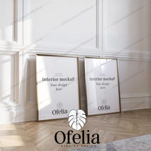 Può includere: Due poster incorniciati in oro con passepartout bianchi e sfondi bianchi. Il testo sui poster recita "Interior Mockup" e "Your design here". I poster sono su un pavimento in legno chiaro con una grande pianta a foglie verdi in primo piano. Il testo "Ofelia" è sotto la pianta.