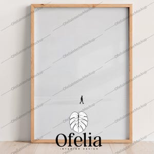 May include: A wooden frame with a white background and a small silhouette of a person walking. The frame is on a wooden surface. The text "Ofelia" is below the frame with the words "INTERIOR DESIGN" underneath.