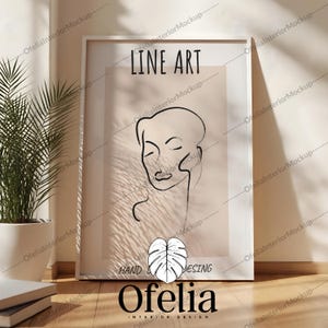 Puede incluir: Una impresión enmarcada en blanco con un dibujo de línea de un rostro de mujer. La impresión tiene el texto "LINE ART" en la parte superior y "HAND DESING" en la parte inferior. El nombre del artista "Ofelia" está impreso en negro debajo de la imagen.