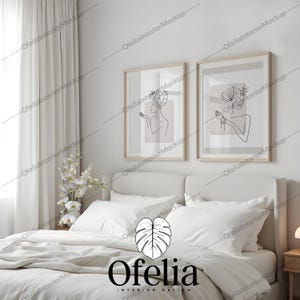 Puede incluir: Una cama blanca con ropa de cama blanca y dos dibujos en blanco y negro enmarcados de mujeres con acentos florales sobre la cabecera. El texto "Ofelia Interior Design" está centrado debajo de la cama.