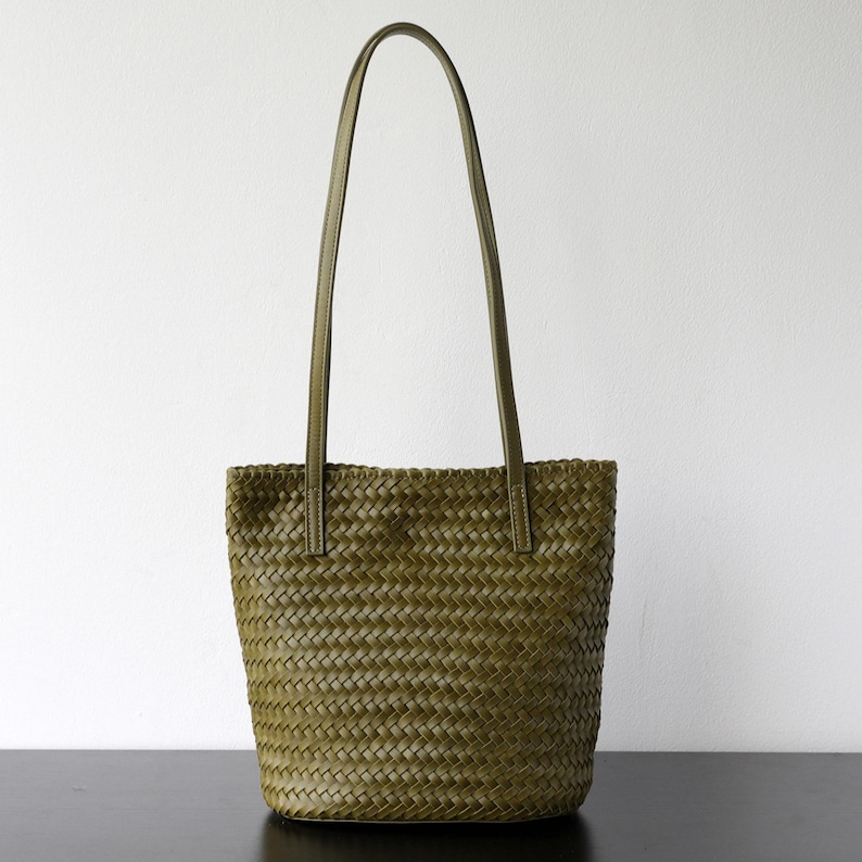 Peut inclure: Sac fourre-tout tiss&eacute; vert olive avec de longues anses. Le sac pr&eacute;sente un motif de tissage en forme de panier et est fabriqu&eacute; dans un mat&eacute;riau durable. Les anses sont de couleur vert olive assortie. Le sac est con&ccedil;u pour transporter des articles.