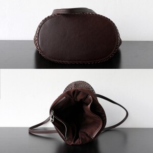 Peut inclure: Un sac &agrave; main en cuir marron fonc&eacute; avec un dessus tress&eacute; et une fermeture &agrave; cordon. Le sac a un fond arrondi et une longue bandouli&egrave;re. L'int&eacute;rieur est d'une teinte plus claire de marron.