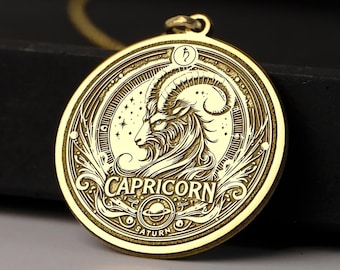 May include: Gold-toned pendant necklace featuring a detailed engraved design of a Capricorn zodiac sign with the words "Capricorn" and "Saturn" inscribed.