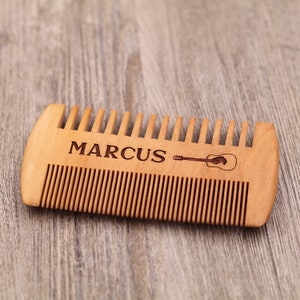May include: A wooden comb with the name "MARCUS" and a guitar design engraved on it.