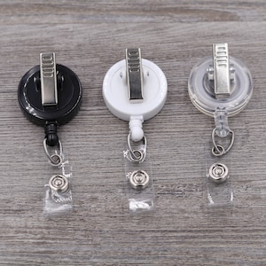 Puede incluir: Tres portagajes retr&aacute;ctiles, uno negro, uno blanco y uno transparente. Cada portagajes tiene un clip de metal y una correa de pl&aacute;stico transparente.